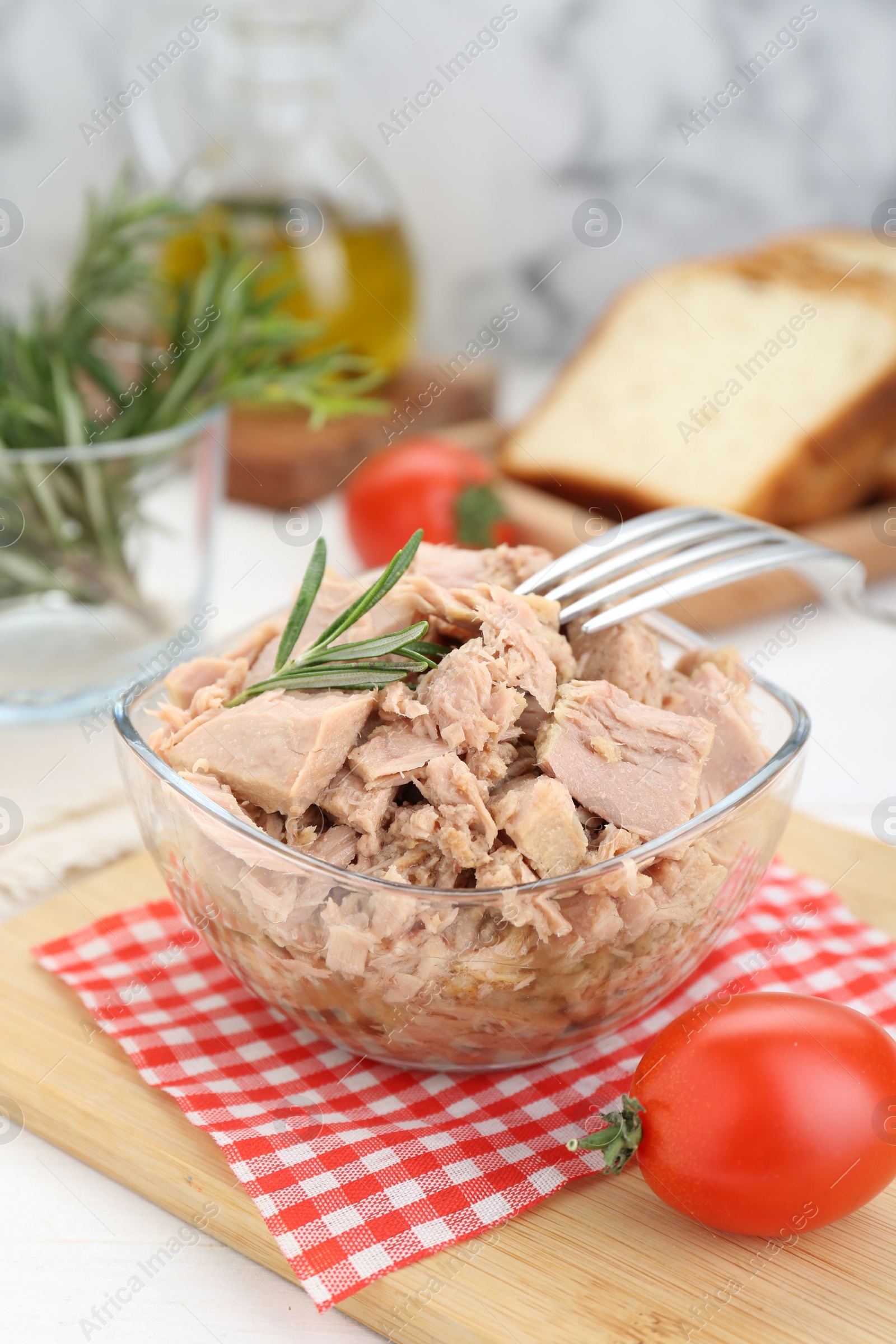 Photo of Bowl with canned tuna and rosemary on white wooden table