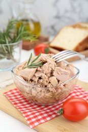 Bowl with canned tuna and rosemary on white wooden table