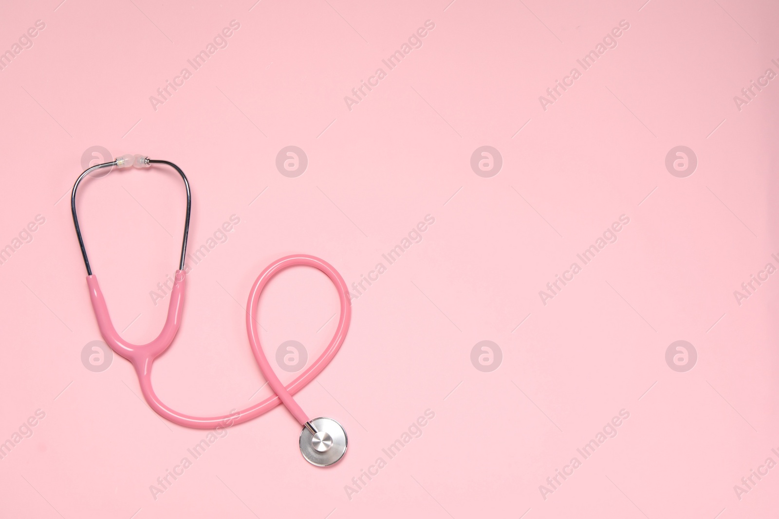 Photo of Stethoscope on pink background, top view. Space for text