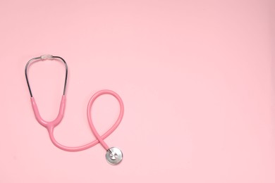 Photo of Stethoscope on pink background, top view. Space for text