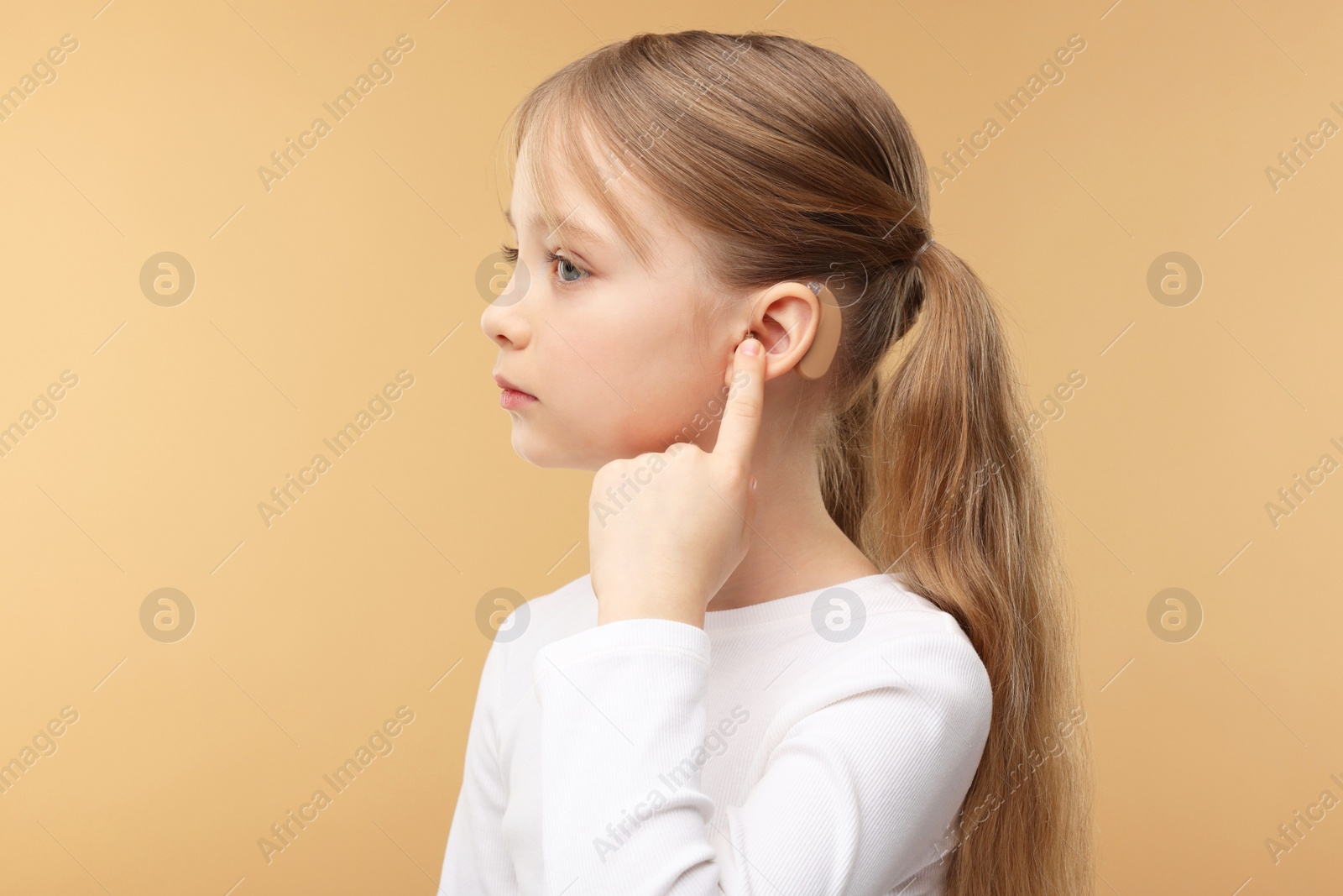 Photo of Little girl with hearing aid on pale brown background