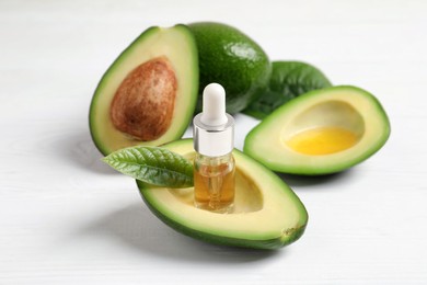 Photo of Essential oil and avocados on white table
