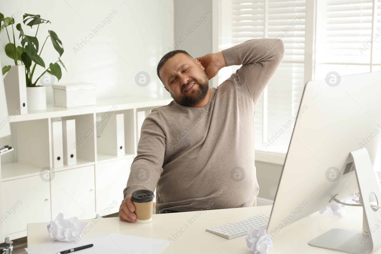 Photo of Lazy overweight office employee procrastinating at workplace