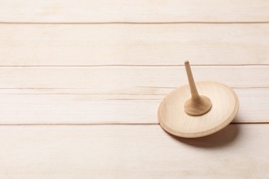 One spinning top on light wooden table, closeup. Space for text