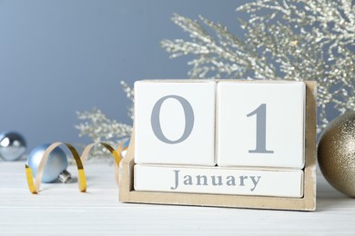 Wooden block calendar and Christmas decor on white table. New Year celebration