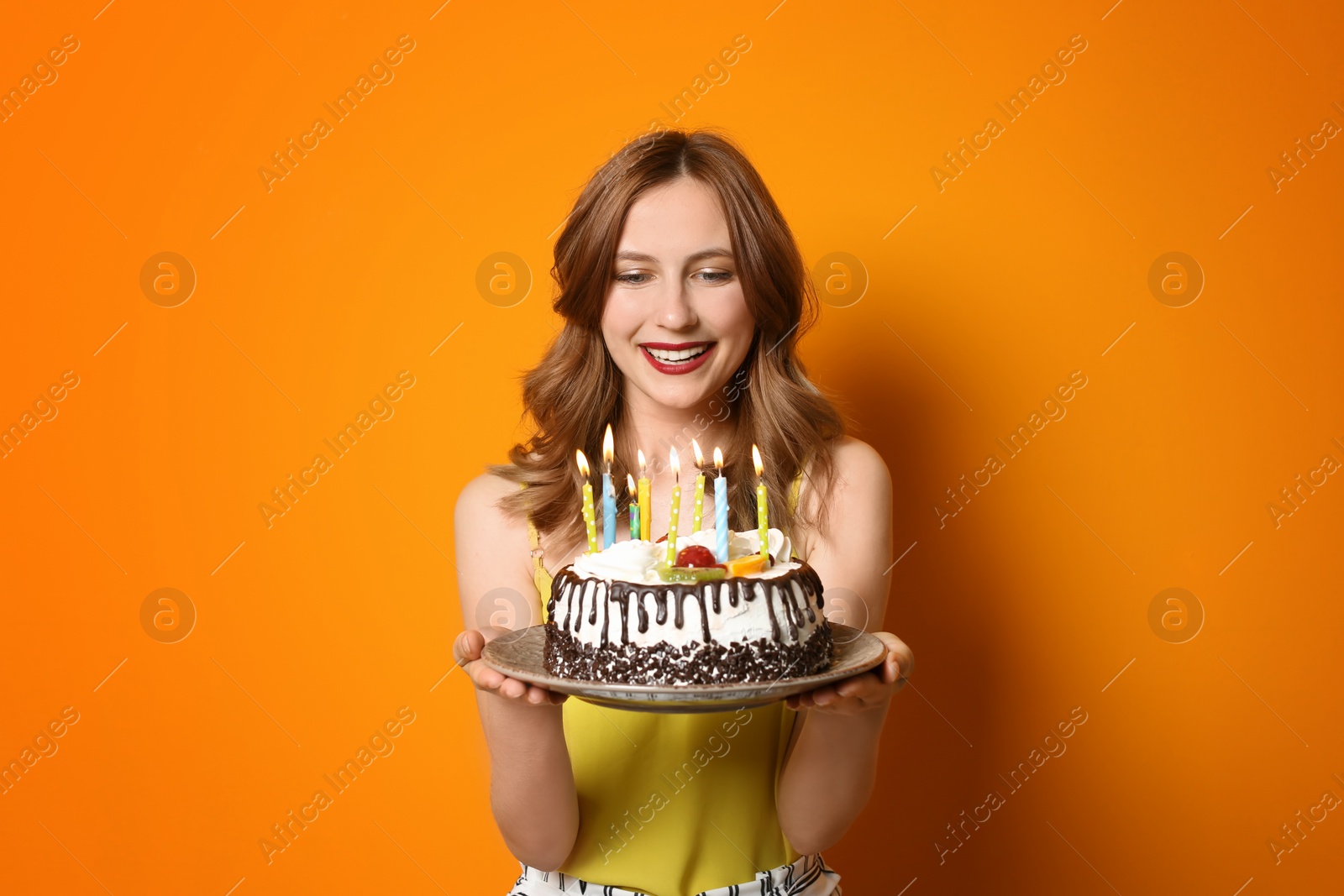 Photo of Young woman with birthday cake on color background