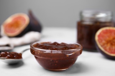 Tasty sweet fig jam and fruits on white marble table, closeup