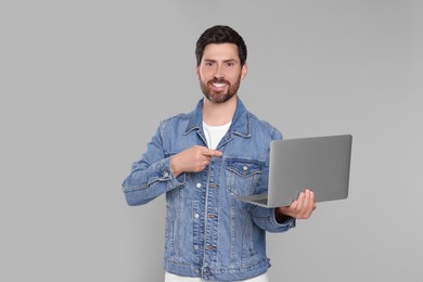 Photo of Happy man with laptop on light grey background