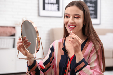 Female beauty blogger applying lipstick at home