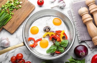 Photo of Tasty fried eggs with vegetables in pan and ingredients on white marble table, flat lay