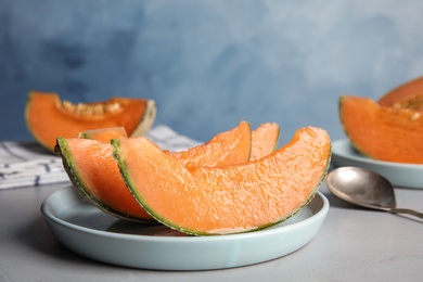Photo of Slices of ripe cantaloupe melon in plate on grey table