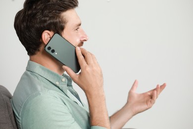 Photo of Handsome man talking on phone at home, space for text