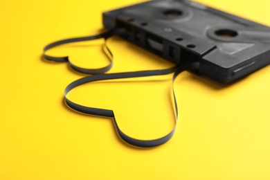 Photo of Music cassette and hearts made with tape on yellow background, closeup. Listening love song