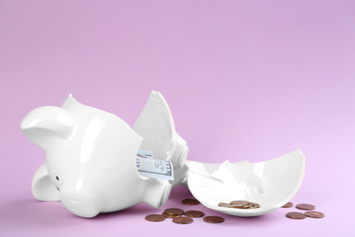 Photo of Broken piggy bank with money on violet background