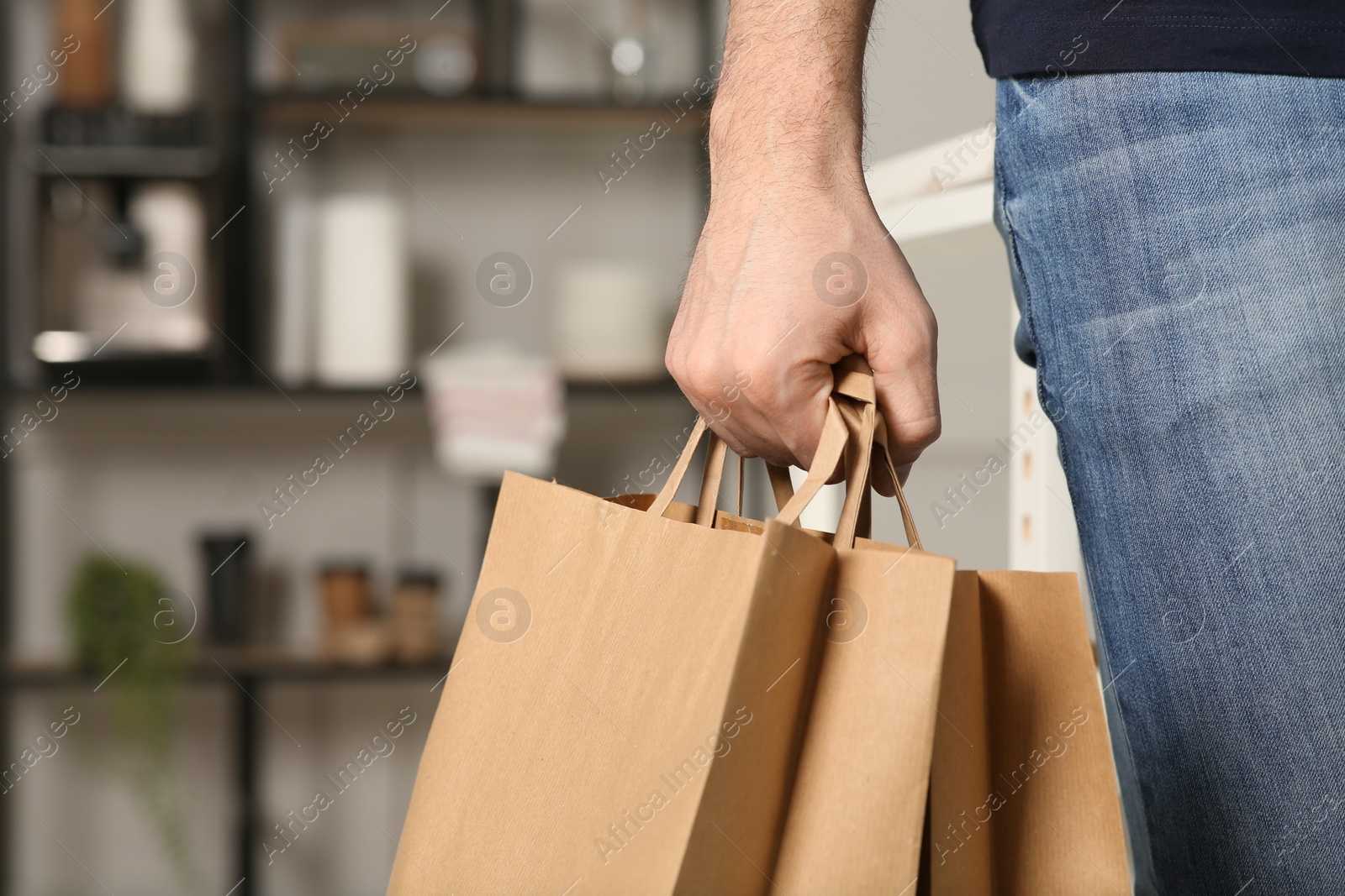 Photo of Man with paper bags indoors, closeup. Space for text