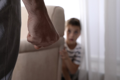 Man threatens his son at home, focus on fist. Domestic violence concept