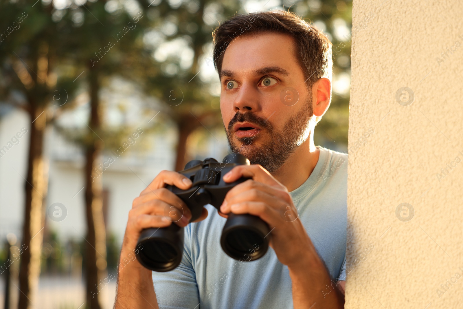 Photo of Concept of private life. Curious man with binoculars spying on neighbours outdoors