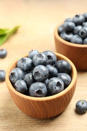 Photo of Bowls of fresh tasty blueberries on wooden table, closeup