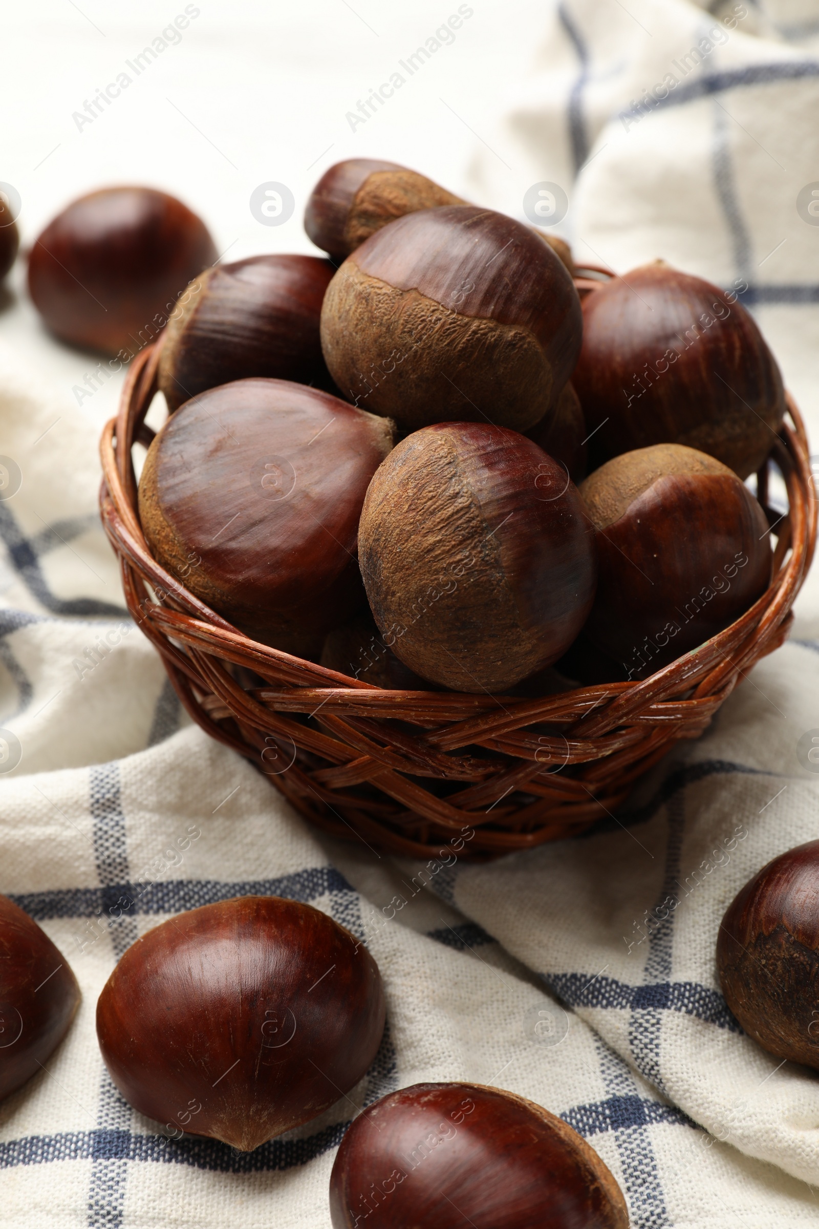 Photo of Sweet fresh edible chestnuts in wicker bowl on table, closeup