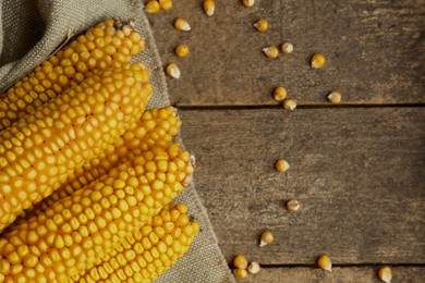 Delicious ripe corn cobs on wooden table, flat lay