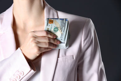 Woman putting bribe into pocket on black background, closeup