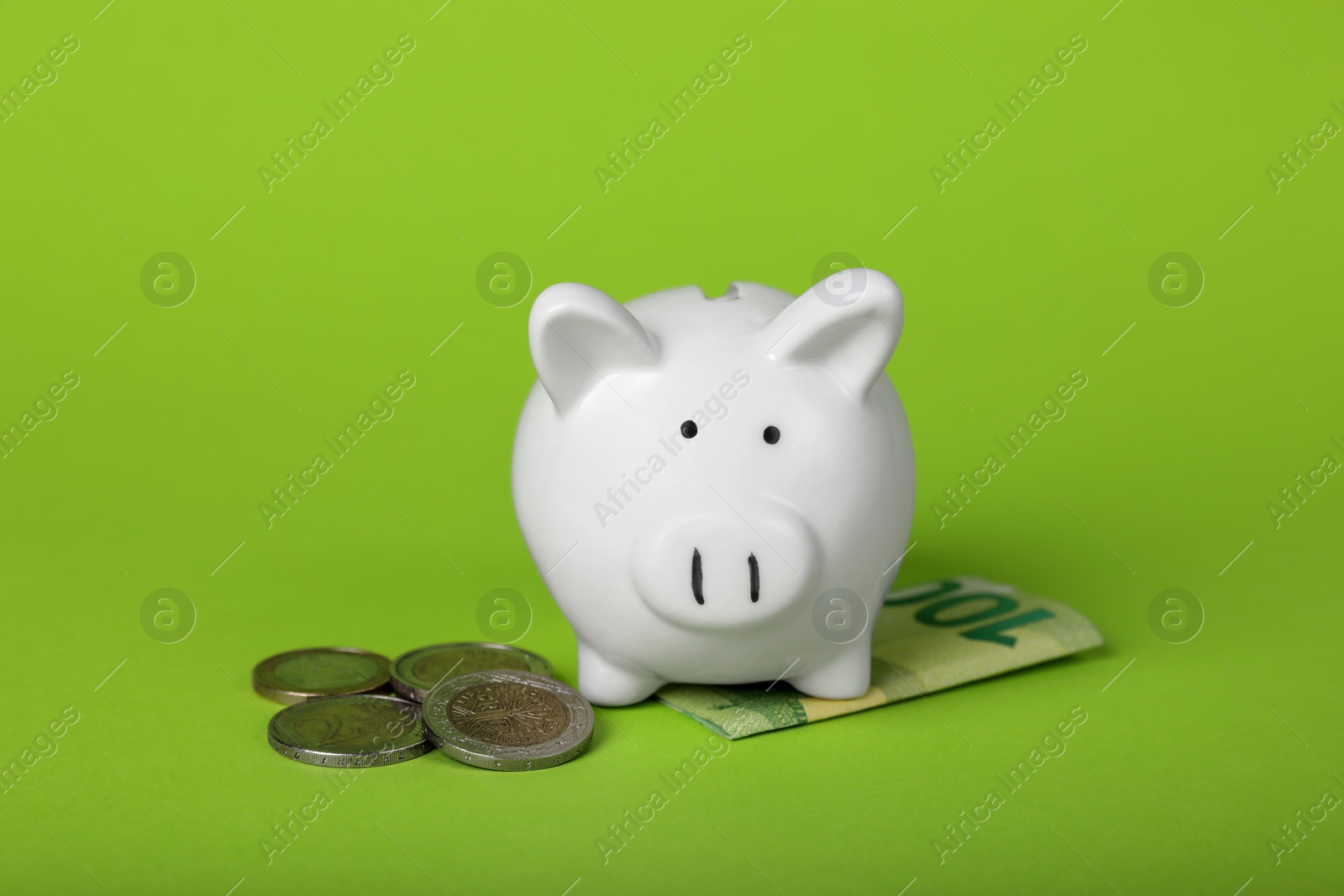 Photo of Ceramic piggy bank, coins and euro banknote on light green background. Financial savings