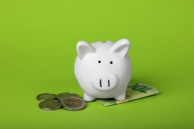 Photo of Ceramic piggy bank, coins and euro banknote on light green background. Financial savings