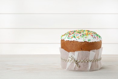 Photo of Traditional Easter cake with sprinkles on white wooden table, space for text