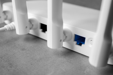 Photo of New modern Wi-Fi router on grey table, closeup