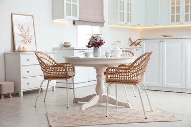 Dining room interior with tea set on round table and wicker chairs