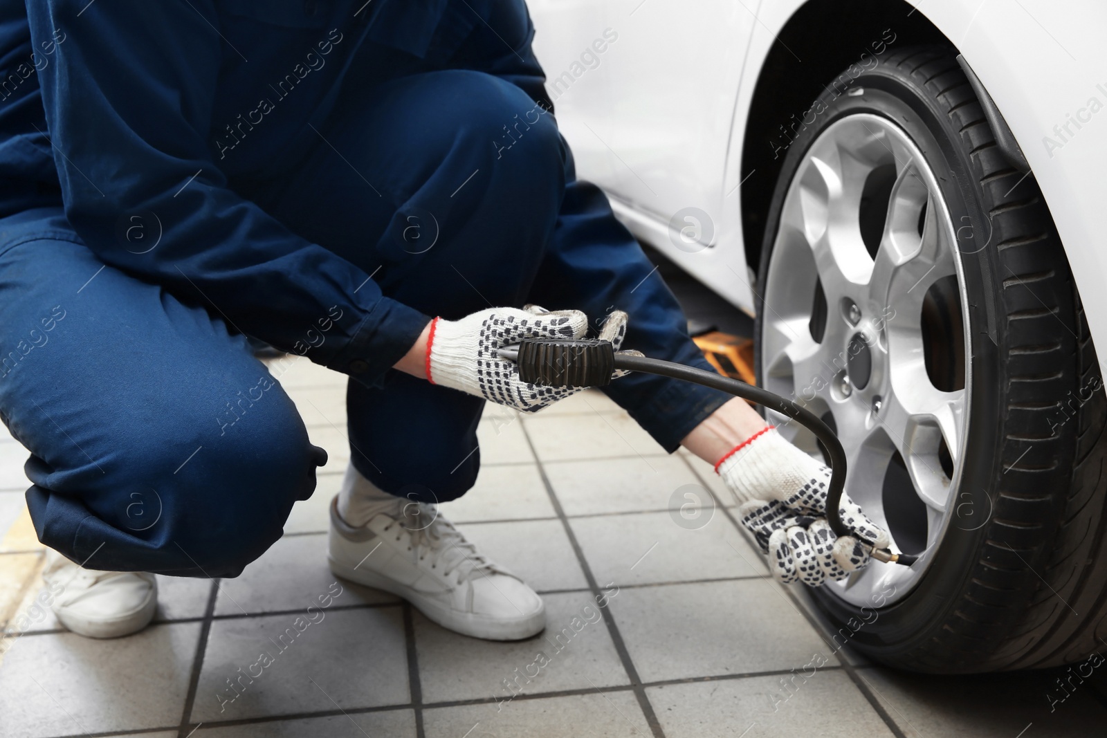 Photo of Mechanic checking tire pressure in service center, closeup