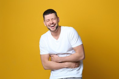 Photo of Handsome man laughing on yellow background. Funny joke