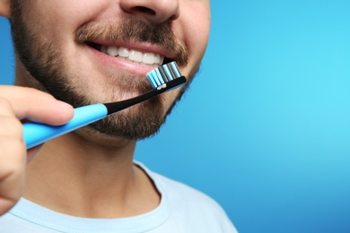 Young man with toothbrush on color background, closeup. Space for text