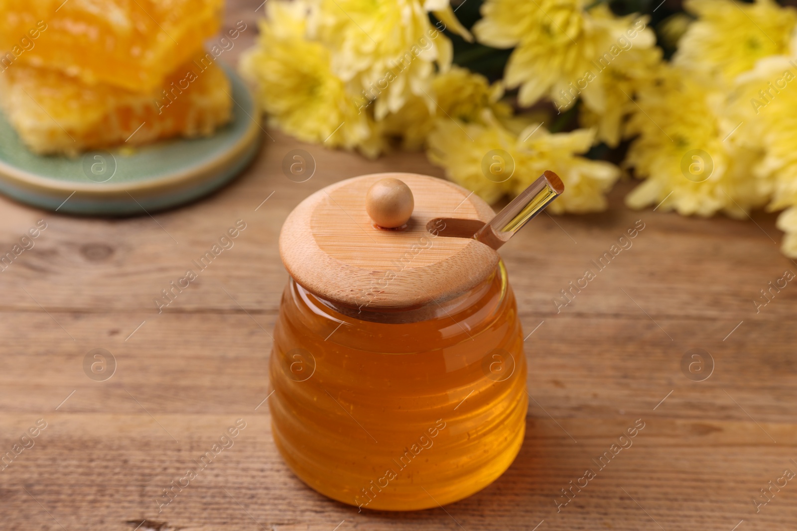 Photo of Sweet golden honey in jar on wooden table