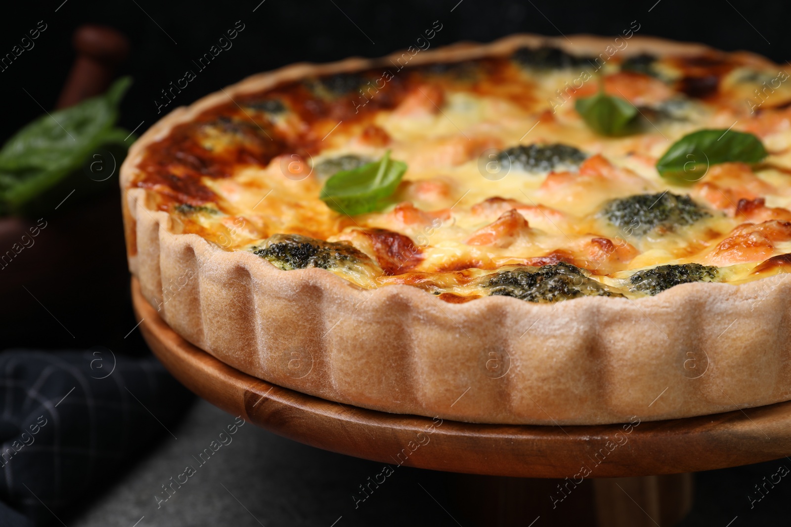 Photo of Delicious homemade quiche with salmon and broccoli on wooden board, closeup