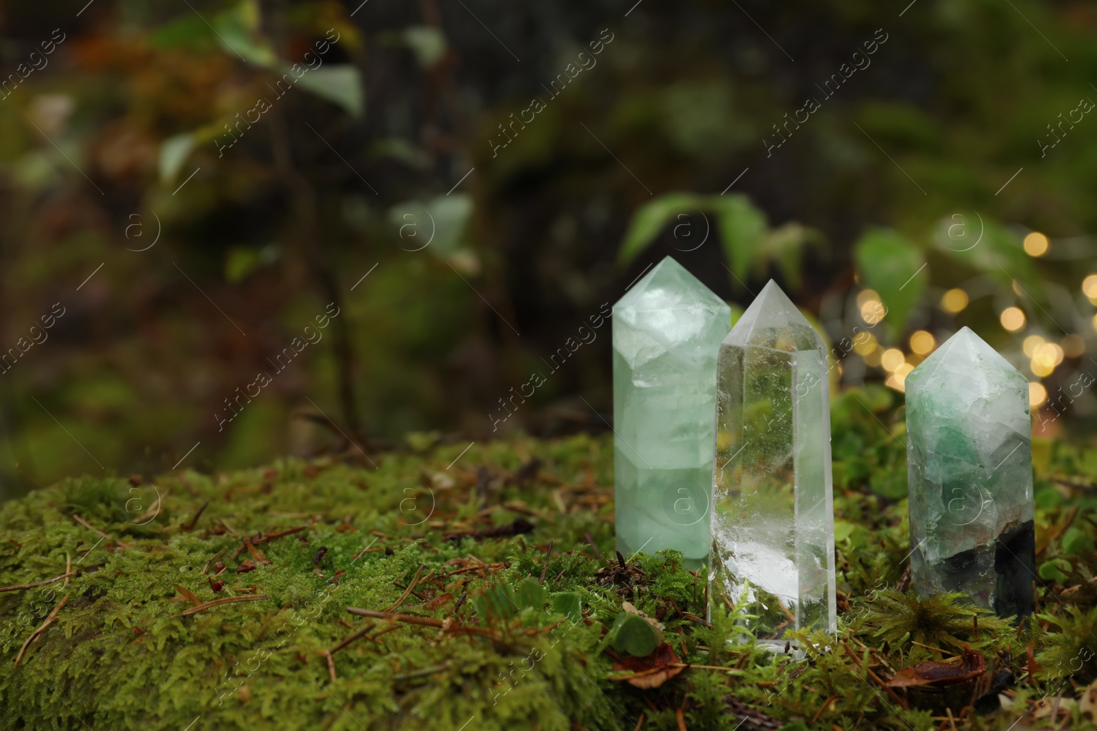 Photo of Different crystals on moss against blurred lights, space for text