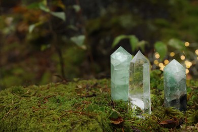 Photo of Different crystals on moss against blurred lights, space for text