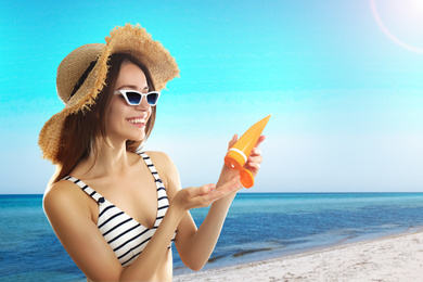 Image of Young woman applying sun protection cream at beach, space for text