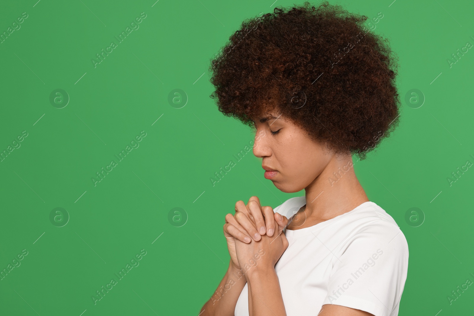 Photo of Woman with clasped hands praying to God on green background. Space for text