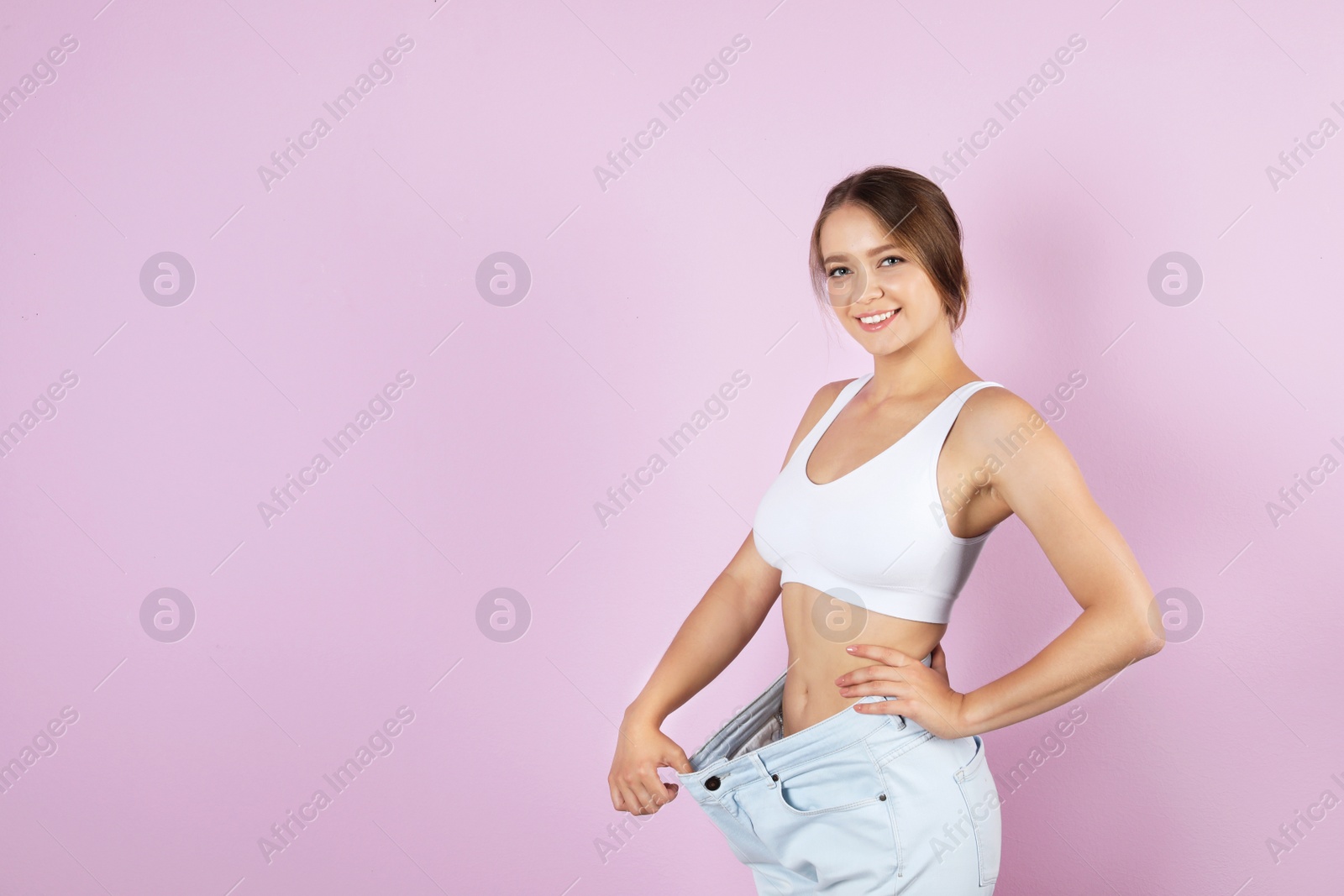 Photo of Young woman wearing oversize pants on color background. Healthy diet