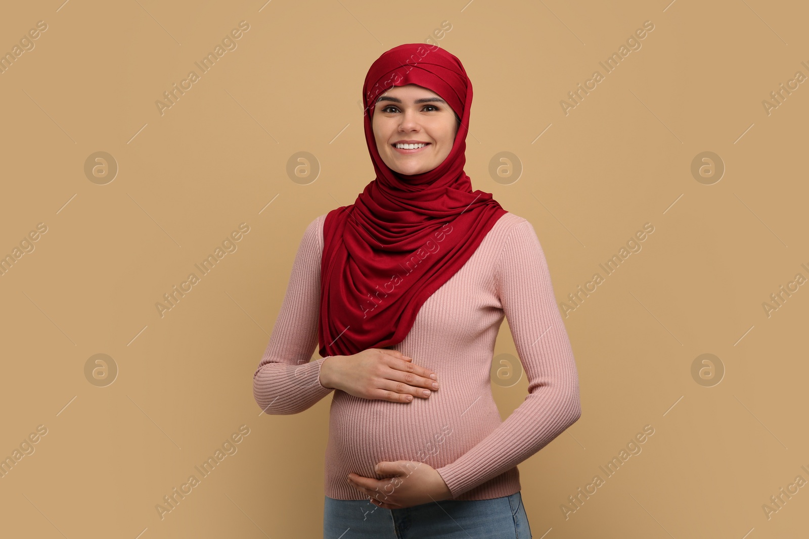 Photo of Portrait of pregnant Muslim woman in hijab on beige background