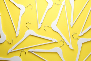 Photo of White hangers on yellow background, flat lay