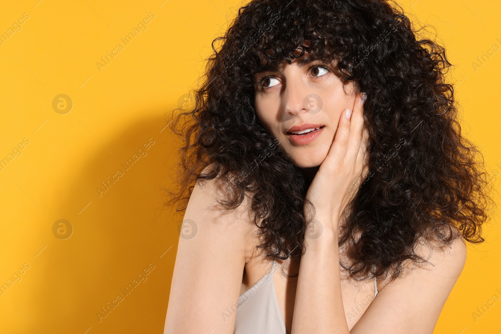 Photo of Beautiful young woman in sunlight on orange background, space for text