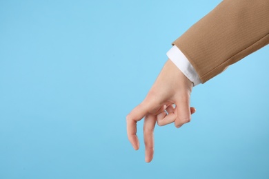 Photo of Businesswoman imitating walk with hand on light blue background, closeup. Finger gesture