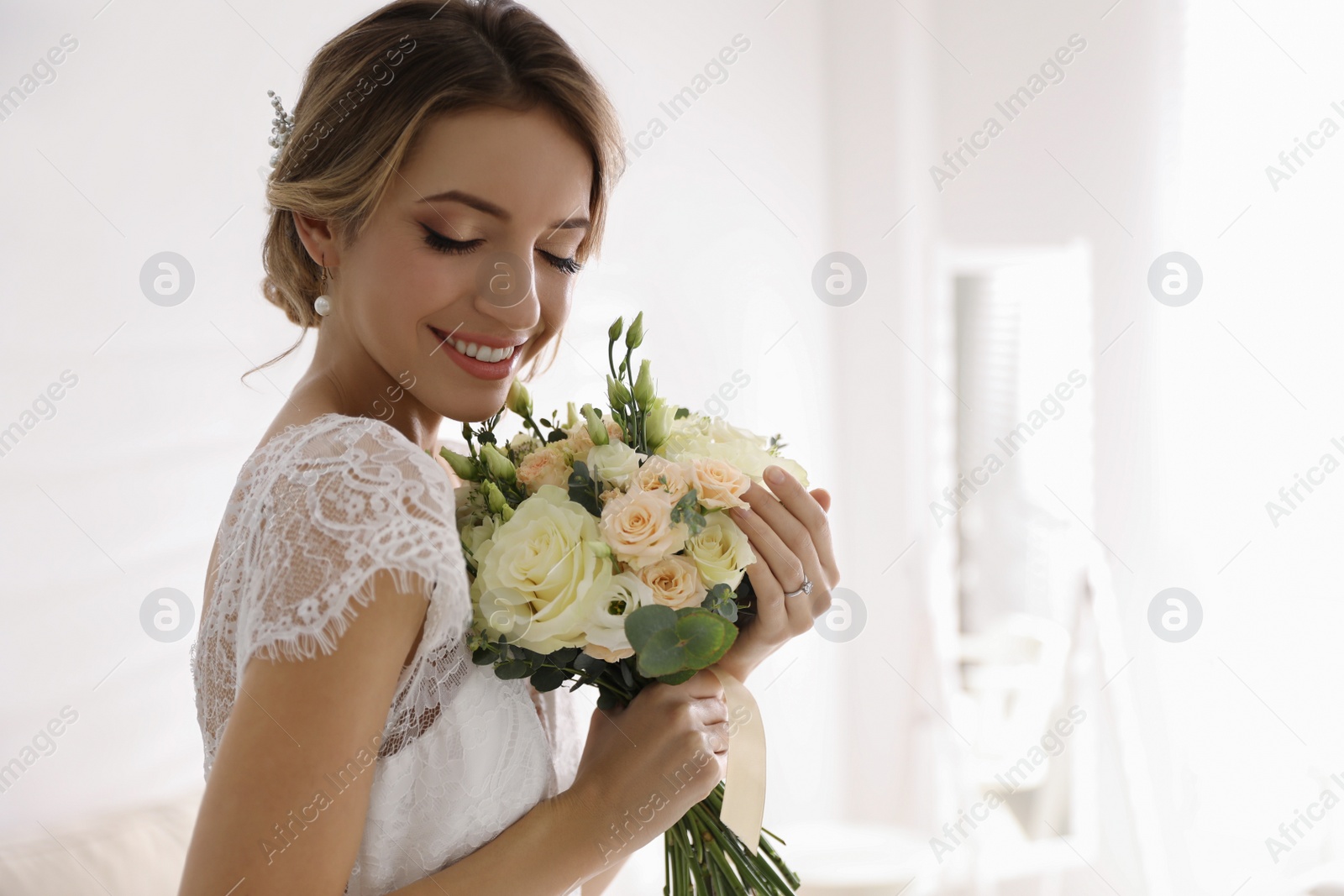 Photo of Gorgeous bride in beautiful wedding dress holding bouquet in room. Space for text