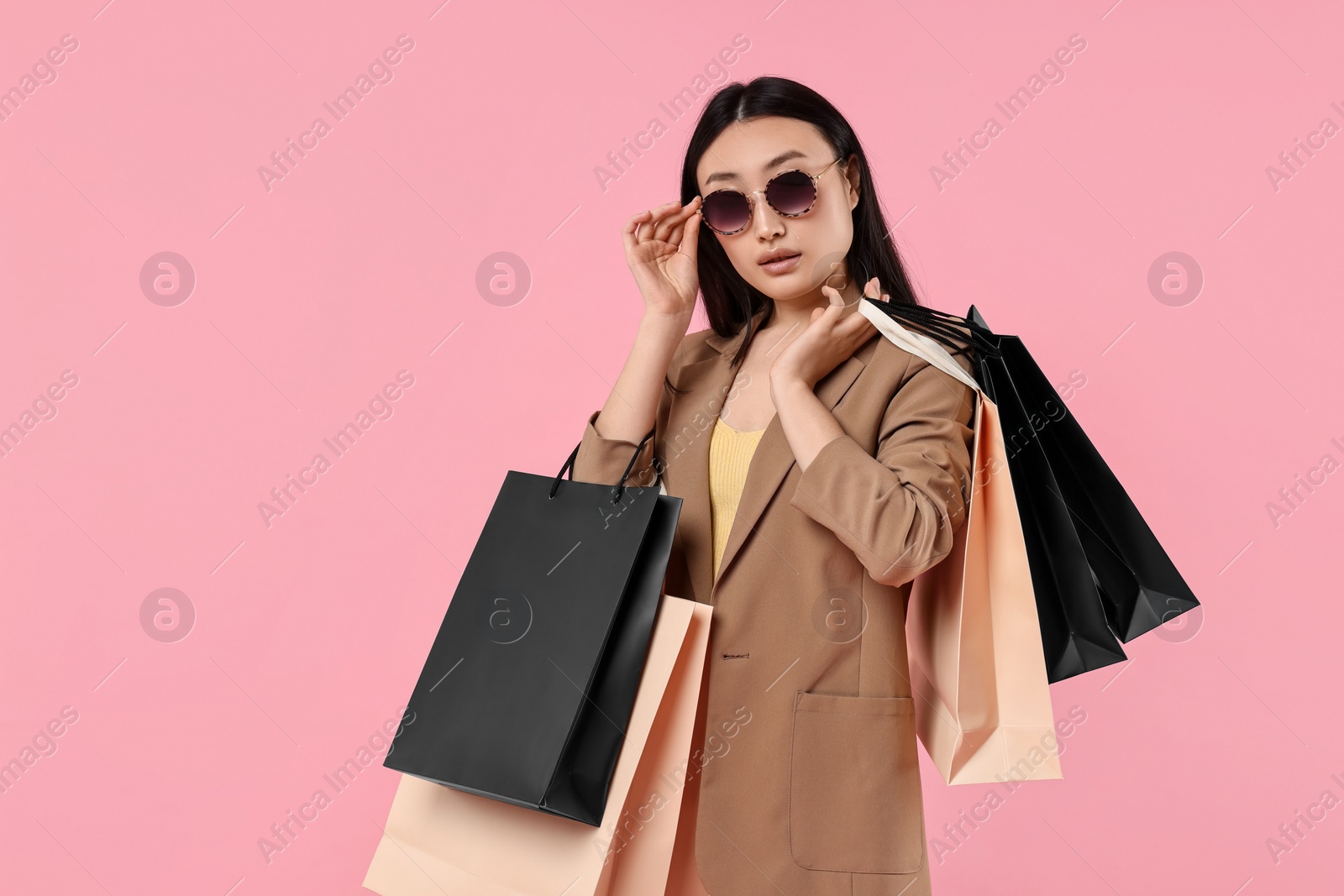 Photo of Beautiful woman with shopping bags on pink background. Space for text