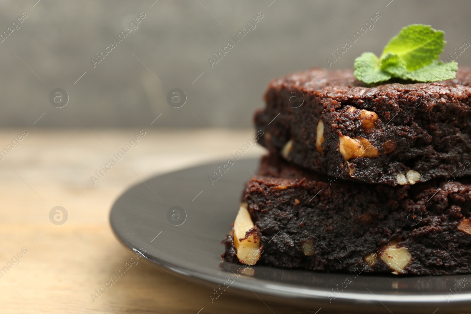 Photo of Delicious brownies with nuts and mint on table, closeup. Space for text