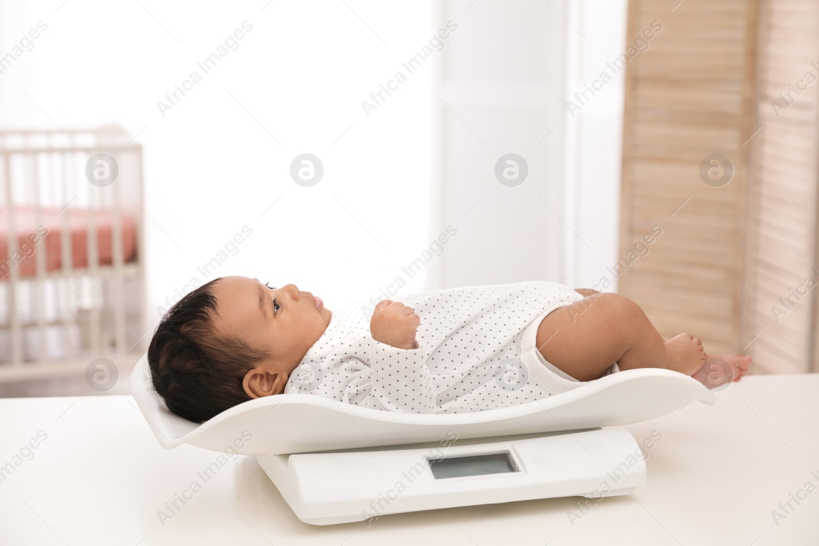 Photo of African-American baby lying on scales in light room