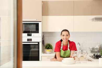 Photo of Beautiful young woman with clean dishes in kitchen