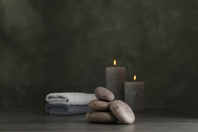 Photo of Spa stones with candles and towel on grey table